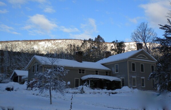A large house with a snow-covered roof and a mountain in the background.