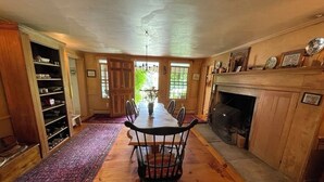 A dining area with a long wooden table, chairs, and a fireplace.