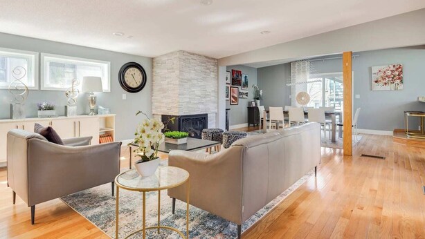 A modern living room with a fireplace, a dining area, and a kitchen visible in the background.