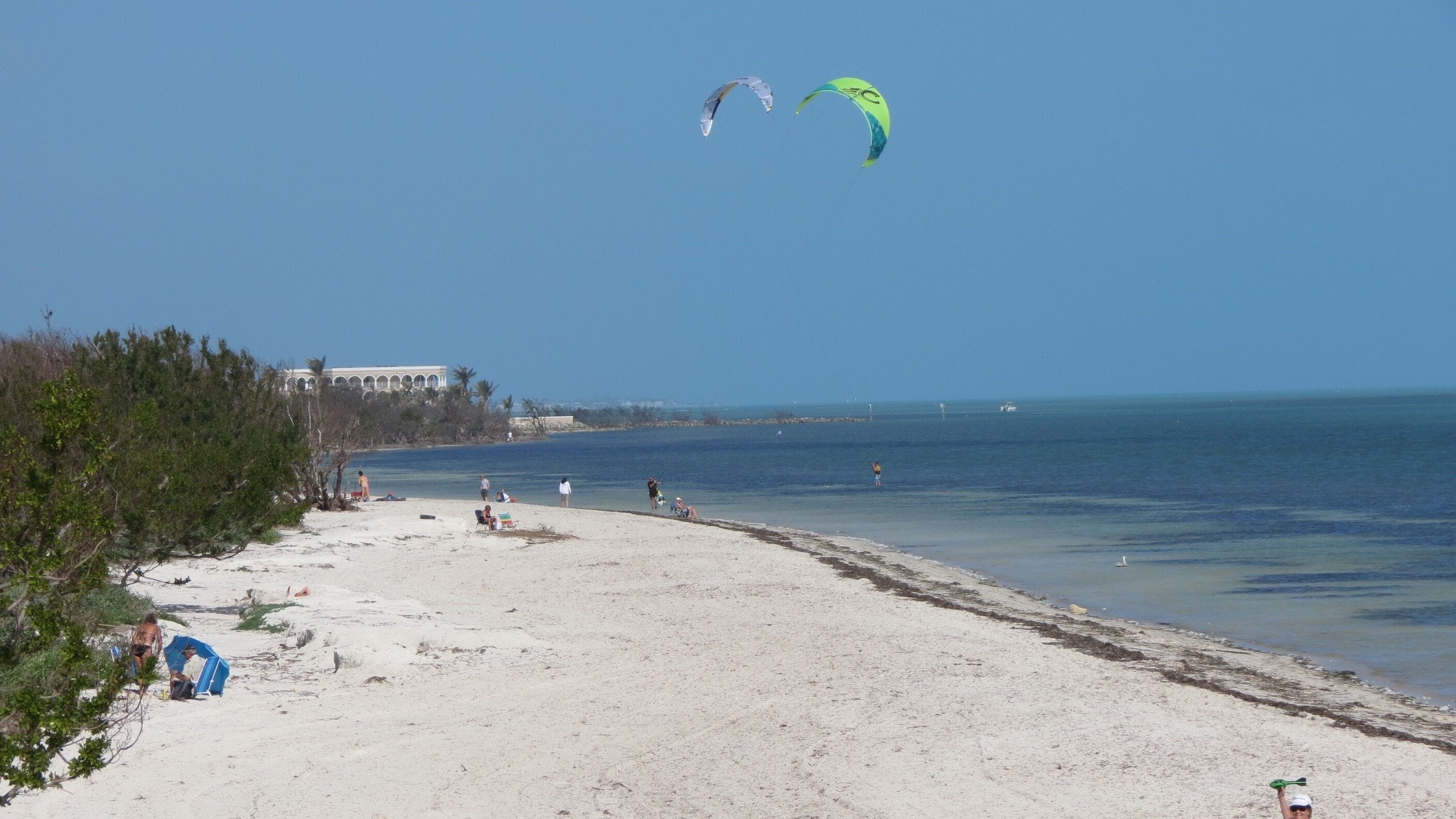 A beach with clear skies, a sandy shore, and a few people.