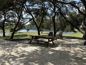 A picnic area with benches and a picnic table, surrounded by trees and a body of water.