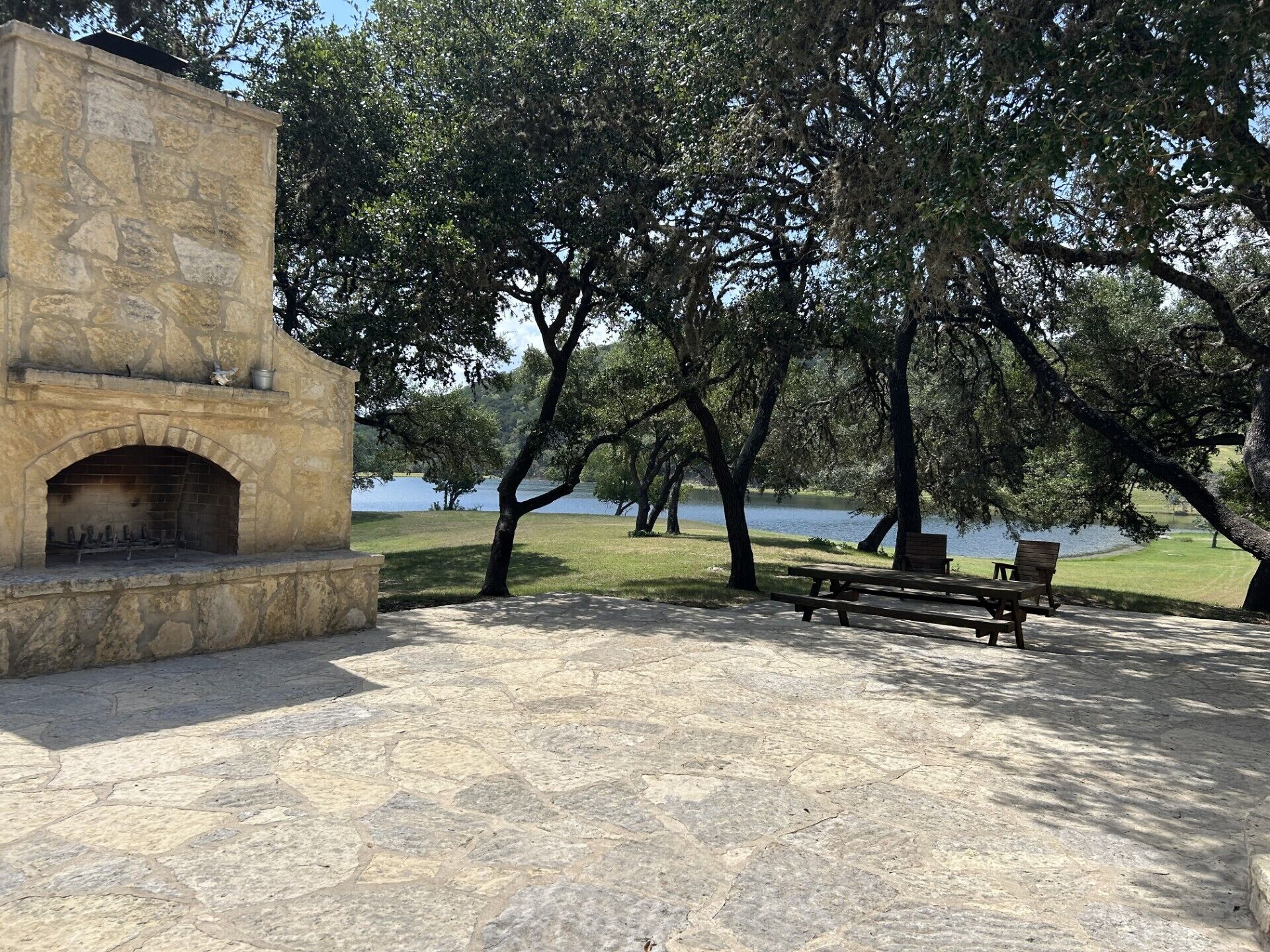 A stone-built outdoor area with a fireplace, picnic tables, and benches.