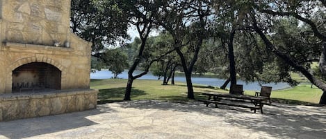 A stone-built outdoor area with a fireplace, picnic tables, and benches.