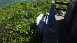 Un mirador de fusta amb barana metàl·lica que domina un paisatge montanyós de vegetació densa i turons llunyans.