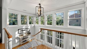 Une pièce spacieuse avec de grandes fenêtres, un escalier en bois et un lustre.