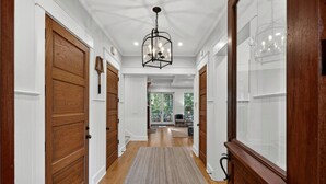 Un couloir avec des portes en bois, un tapis et un lustre.