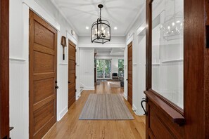 A hallway with wooden doors, a rug, and a chandelier.