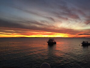 A sunset over a calm sea with two boats.