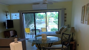 A living room with a glass-top dining table, a sofa, a TV, and a ceiling fan. - Well-maintained Sand Dollar Oceanfront Condo F-9 with new kitchen (Kralendijk)