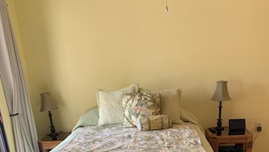 A neatly arranged bedroom with a bed, two bedside tables, a lamp, and a small table with a basket. - Well-maintained Sand Dollar Oceanfront Condo F-9 with new kitchen (Kralendijk)