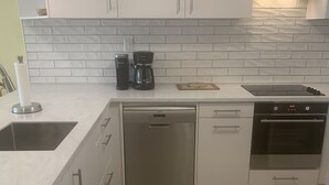A modern kitchen with white cabinets, a dishwasher, an oven, and a coffee maker. - Well-maintained Sand Dollar Oceanfront Condo F-9 with new kitchen (Kralendijk)