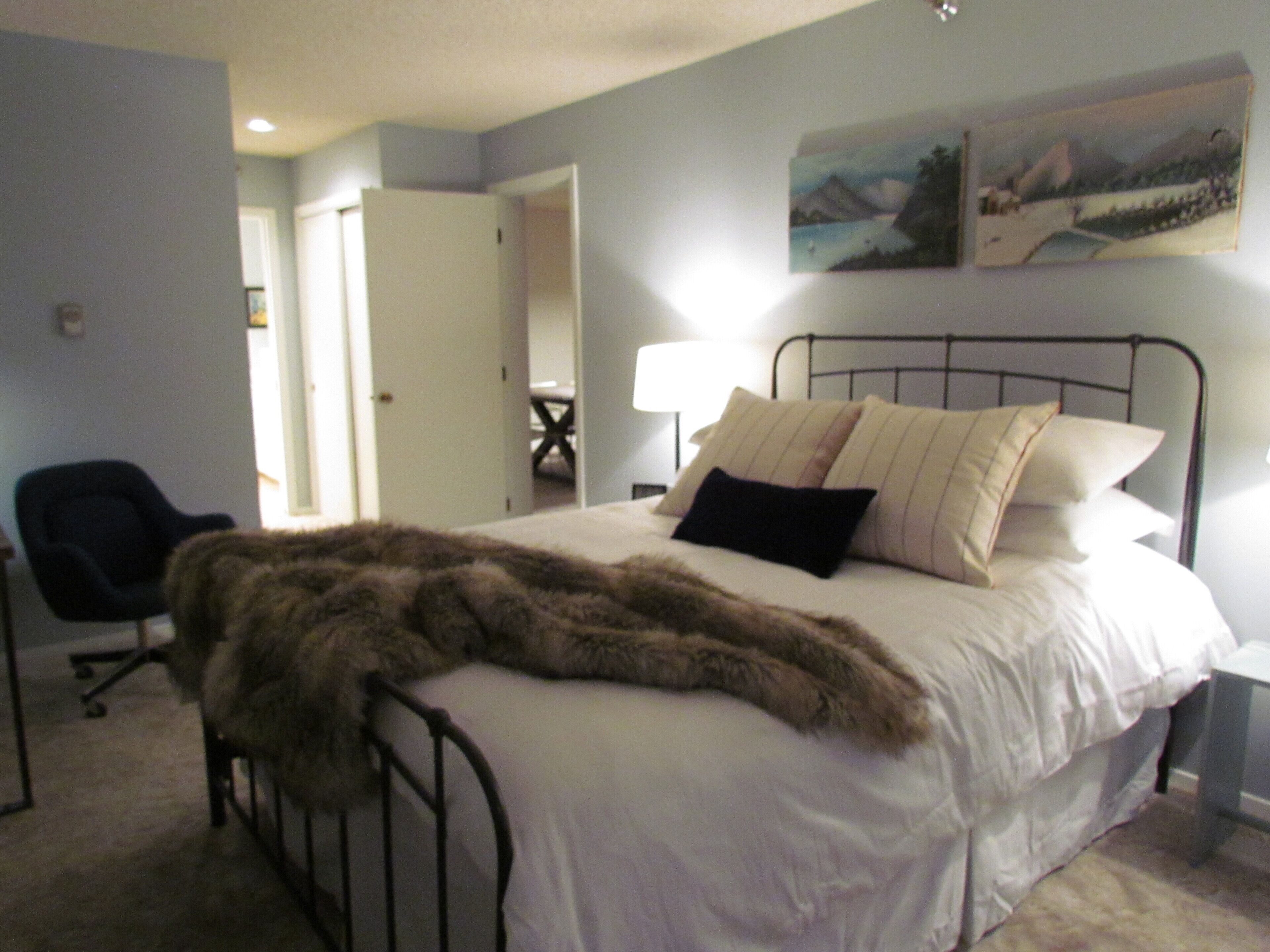 A bedroom with a bed, a chair, and a painting on the wall.