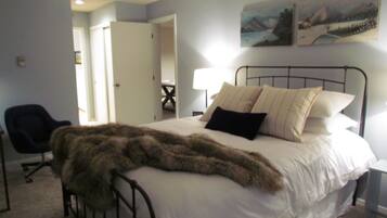 A bedroom with a bed, a chair, and a painting on the wall.