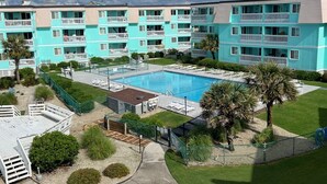 Ein mehrstöckiges Wohngebäude mit Schwimmbad, grünen Rasenflächen und einer umzäunten Terrasse.