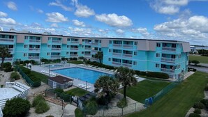 Ein mehrstöckiges Hotel mit Schwimmbad, Balkonen und einem gepflegten Rasen.