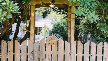 A wooden pergola with a picket fence in front, surrounded by lush greenery.