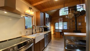 A modern kitchen with stainless steel appliances, wooden cabinets, and a large window providing natural light.
