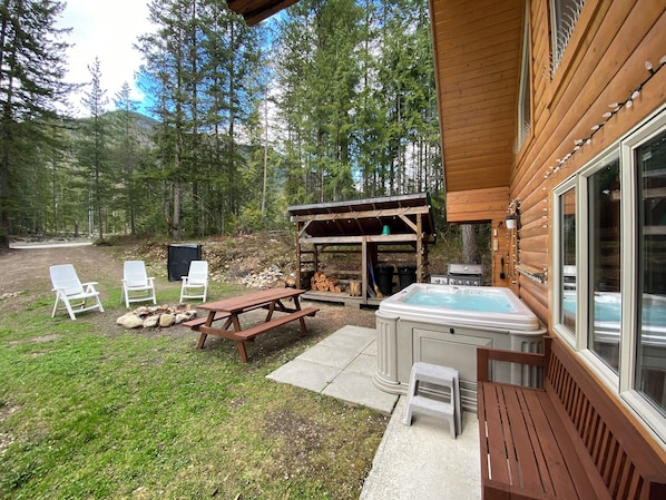 Una cabaña de madera con jacuzzi, mesa de picnic y sillones de descanso.