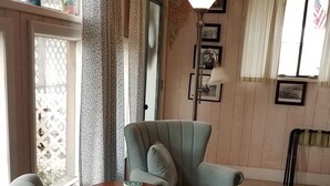 Un salon chaleureux avec un fauteuil gris, un plaid bleu à motifs et une table basse en bois.