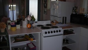 Une cuisine de taille réduite, avec un fourneau blanc, un réfrigérateur et divers ustensiles et appareils de cuisine.