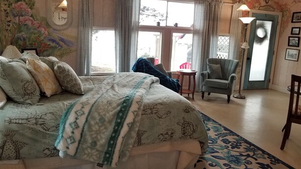 Une chambre à coucher avec un lit, une chaise, une table et une fenêtre.