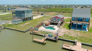 Propiedad frente al agua con piscina, muelle y dos edificios principales.
