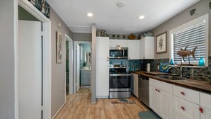 Una cocina moderna con gabinetes blancos, electrodomésticos de acero inoxidable y decoración en la pared.
