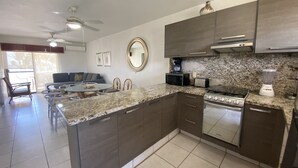 Una cocina moderna con armarios oscuros, encimera de granito, horno empotrado y microondas.