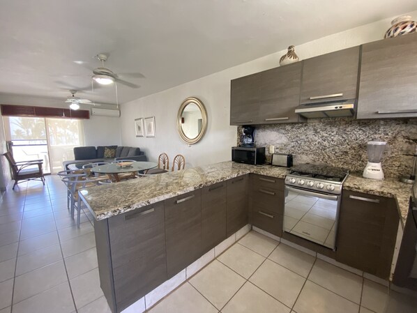 A modern kitchen with dark cabinetry, a granite countertop, a built-in oven, and a microwave.