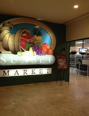 A wall sign for Sunset Market with a colorful display of fruits and vegetables.