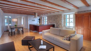 Un'ampia zona giorno con soffitto in legno, parete in pietra, divano, tavolino da caffè e zona pranzo con tavolo e sedie.