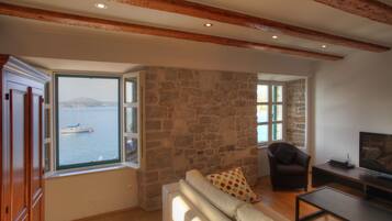 A living room with a stone wall, wooden beams, a sofa, a chair, and a television.