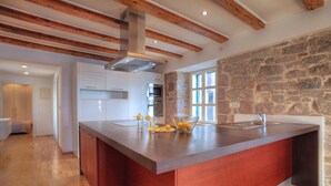 Una cucina moderna con una grande isola, parete in pietra e travi in legno.