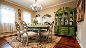 A dining room with a wooden table, four chairs, a chandelier, a green cabinet, and a patterned rug. - Your Next 5 Star Get Away! (Little Rock)