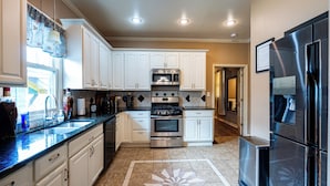 A modern kitchen with white cabinets, stainless steel appliances, and a patterned floor. - Your Next 5 Star Get Away! (Little Rock)