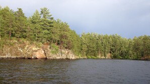 Un lac paisible, bordé d’une rive rocheuse et entouré d’une forêt dense.