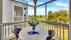 A covered outdoor area with a table, chairs, and a vase of flowers. - Ideal Ocean Point Location- Close to Pool + Beach (Isle Of Palms)