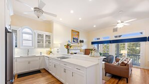 A spacious kitchen with white cabinetry, a large island, and a dining area with a brown leather couch. - Ideal Ocean Point Location- Close to Pool + Beach (Isle Of Palms)