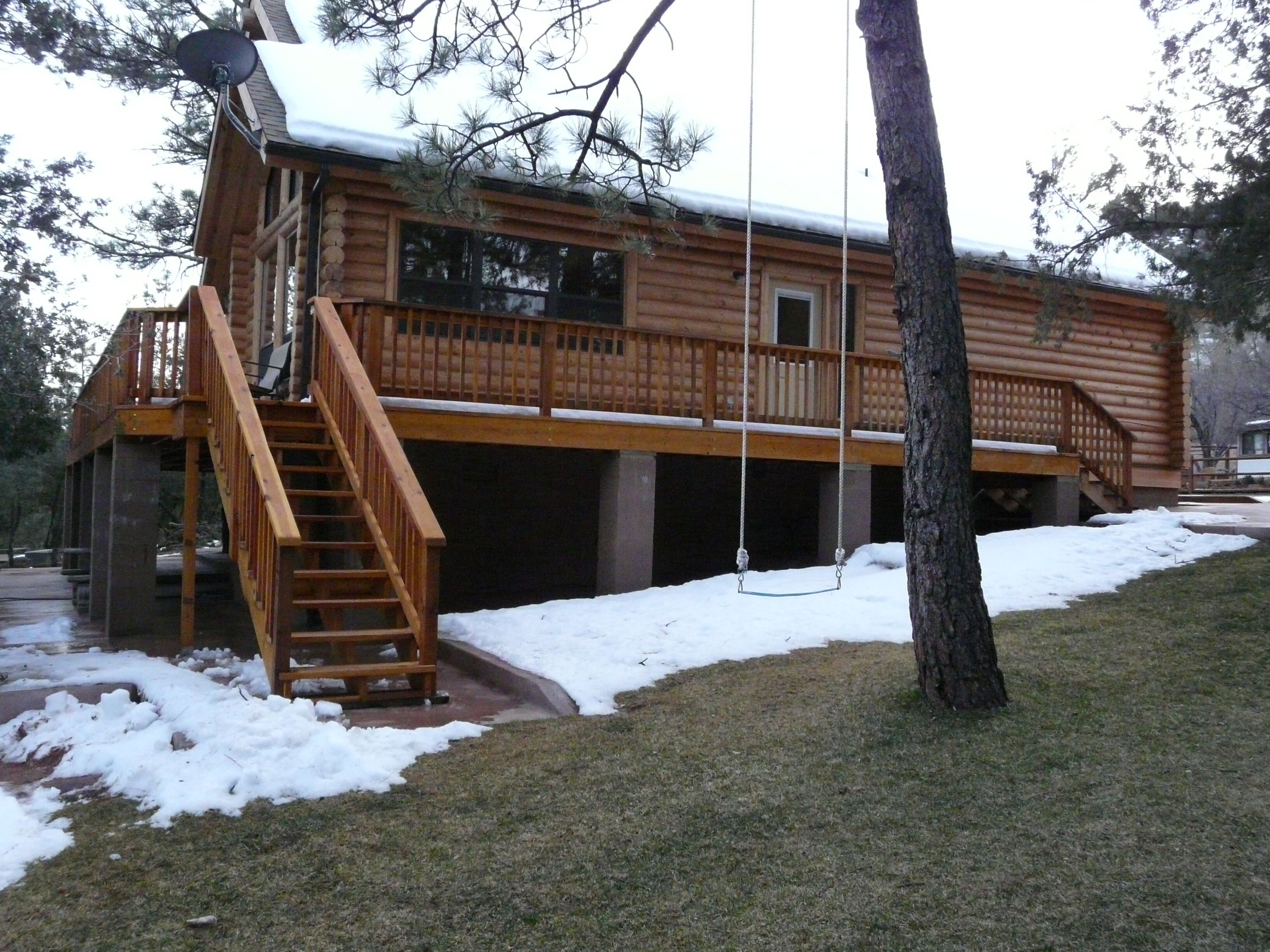 A log cabin with a wooden deck, a swing, and a covered porch area.