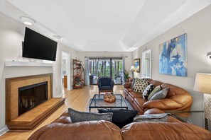 A spacious living room with a fireplace, leather sofa, and a flat-screen TV.