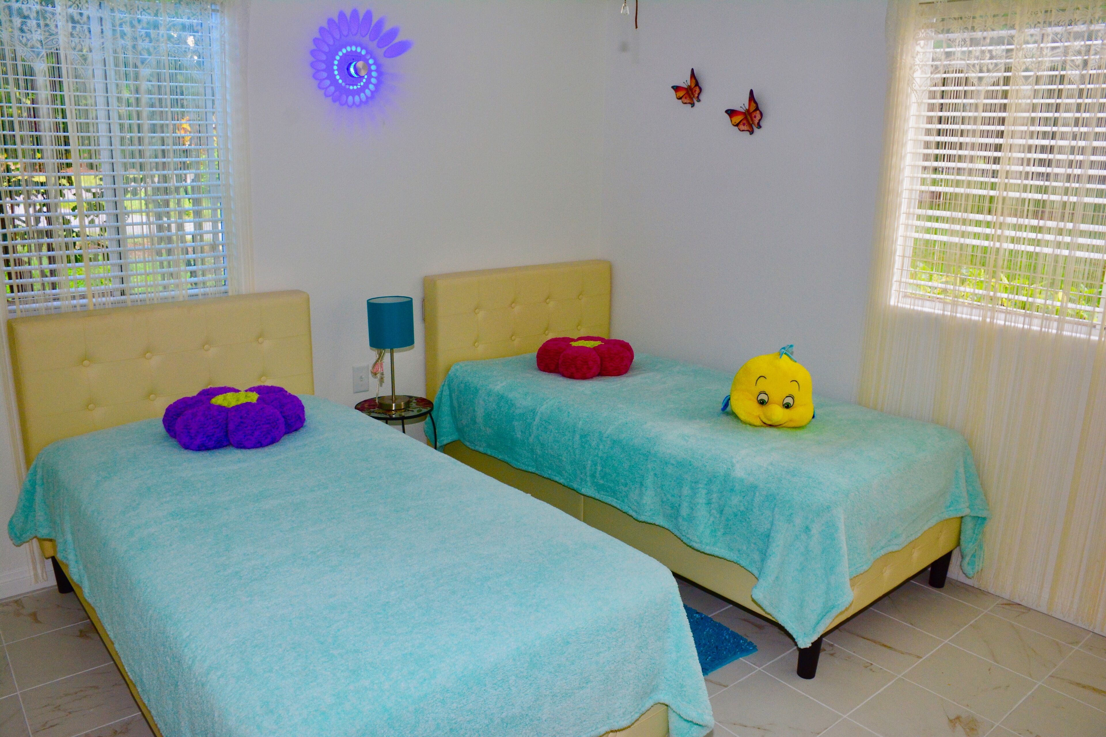 A bedroom with two beds, each with a different colored pillow and a decorative item on top.