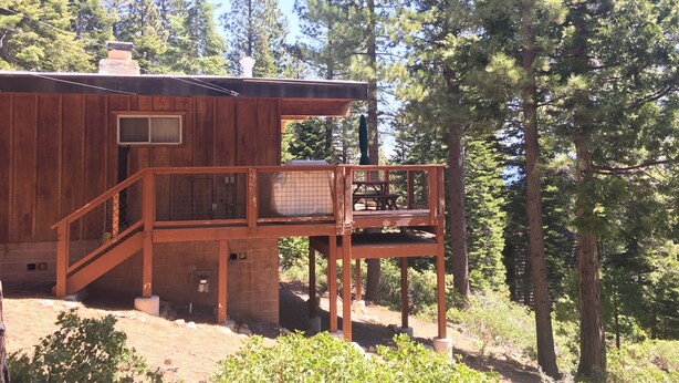 A wooden cabin with a balcony, surrounded by tall pine trees. - Tahoe City Cabin~Spectacular Lake View! Walk to Lake and City * WIFI* (Tahoe City)