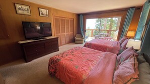 A bedroom with two beds, a TV, a dresser, and a balcony with outdoor seating. - Tahoe City Cabin~Spectacular Lake View! Walk to Lake and City * WIFI* (Tahoe City)