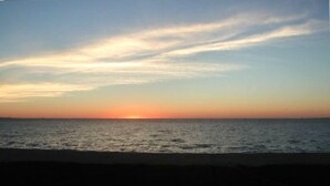 A sunset over the ocean with a clear sky.