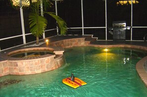 Ein Schwimmbecken mit Whirlpool, Grill und einer Sitzgelegenheit mit Stühlen und Tisch.