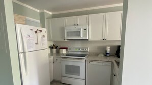 A compact kitchen with white appliances, including a refrigerator, microwave, stove, and dishwasher.