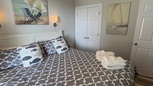 A bedroom with a bed, a ceiling fan, artwork on the walls, and a door.