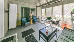 A sunroom with wicker furniture, a table with a glass top, and large windows.