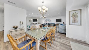 A modern kitchen with white cabinets, a dining table with chairs, and a chandelier.
