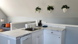 Une cuisine moderne avec des meubles blancs, un plan de travail en marbre et un ventilateur de plafond.